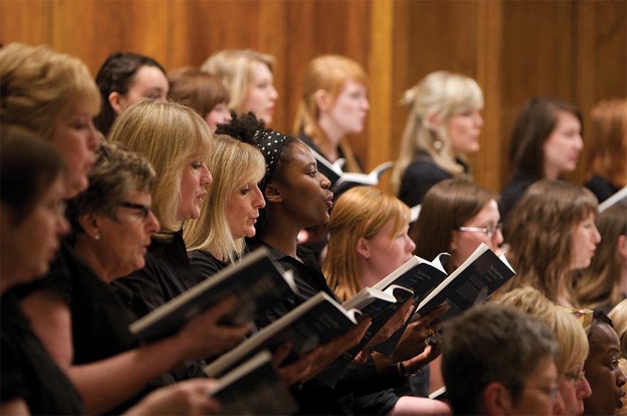 Members of the NTU choir holding music books and singing.